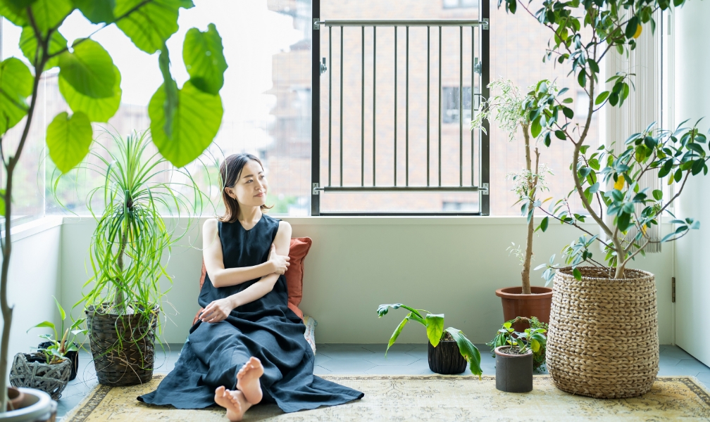 観葉植物に囲まれたリラックスする女性