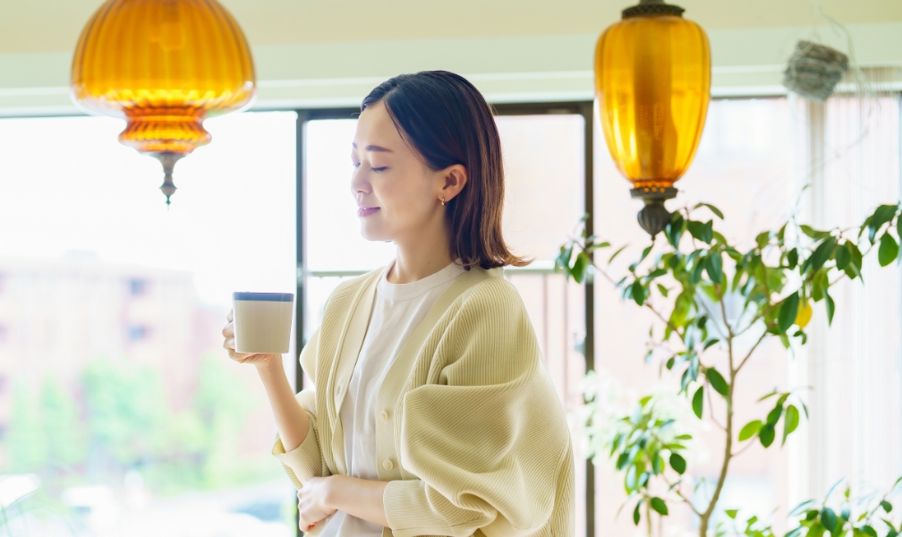 室内でコーヒーを持つ女性